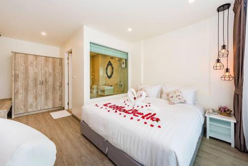 a bedroom with a large white bed with red bows on it at LullaBella Hotel Patong,Nanai Road in Patong Beach