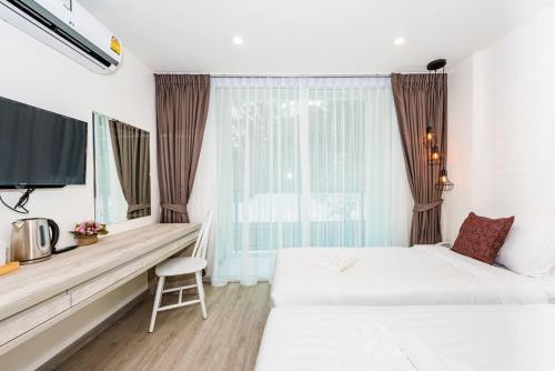 a hotel room with two beds and a window at LullaBella Hotel in Patong Beach
