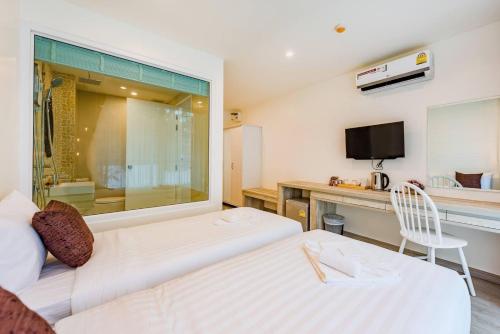a hotel room with a bed and a desk and a tv at LullaBella Hotel Patong,Nanai Road in Patong Beach