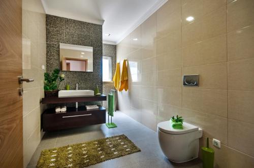 a bathroom with a toilet and a sink and a mirror at Villa Viana by Villa Plus in Lagoa