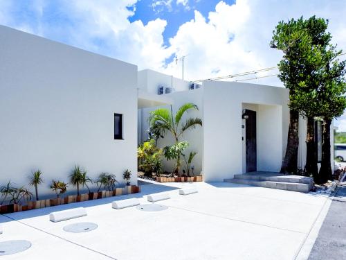 a white house with a courtyard with trees at villa LIFE INDAH sumuide in Nago