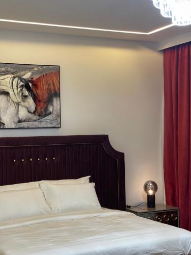 MK Resort في الدوحة: غرفة نوم بسرير ولوحة جواد