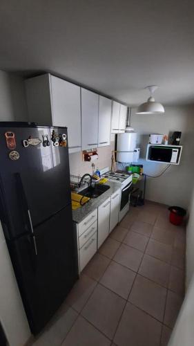 een keuken met een zwarte koelkast en witte kasten bij Departamento super comodo y tranquilo in La Cieneguita