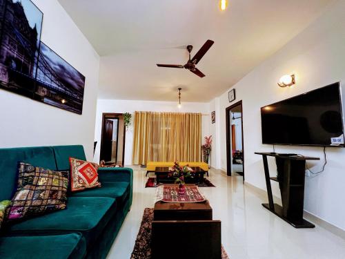 uma sala de estar com um sofá verde e uma televisão de ecrã plano em Luxurious 3BHK vacation home amidst the city. em Mangalore