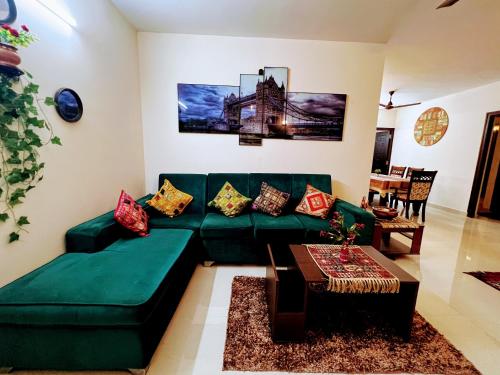 a living room with a green couch and a table at Luxurious 3BHK vacation home amidst the city. in Mangalore