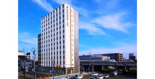 Kuretake Inn Premium Shizuoka Annex في شيزوكا: مبنى أبيض طويل وبه سيارات في مدينة