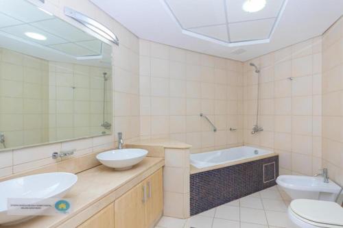 a bathroom with two sinks and a tub and a toilet at Palm Jumeirah Dubai 2 Bed in Dubai