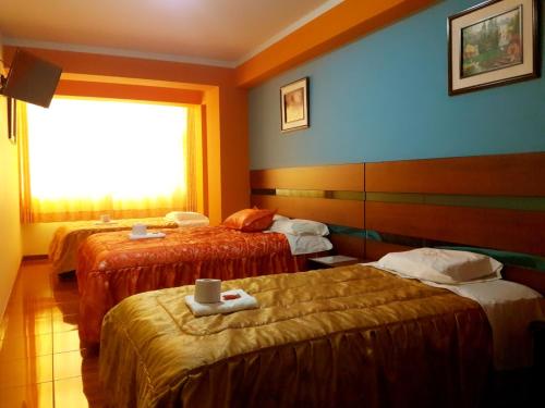 a hotel room with three beds and a window at Tesoro Suite in Tacna