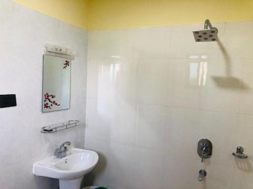 uma casa de banho branca com um lavatório e um chuveiro em Hotel Happy Land em Chitwan