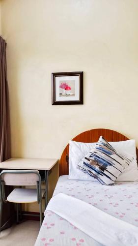 a bedroom with a bed and a table and a desk at Heart Hotel and Services in Dumaguete