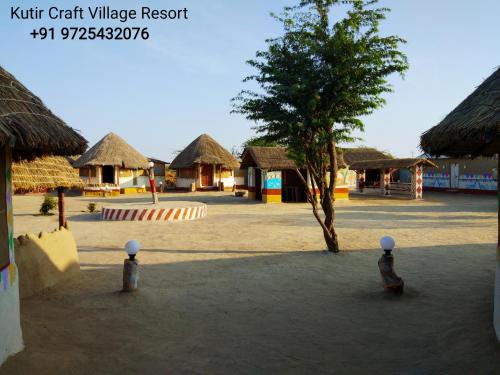 a village with thatched huts and a tree at Kutir Craft Village Resort in Bherandiāla