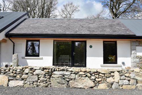 a white house with a stone wall at K2Cottages in Kilday