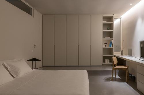 a bedroom with a large white bed and a desk at Aesthesis Boutique Villa Trace in Fira