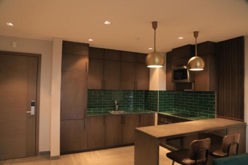 a kitchen with brown cabinets and a green tiled wall at Zara Garden Hotel and Apartments in Kampala
