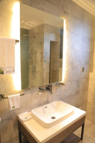 a bathroom with a white sink and a mirror at Zara Garden Hotel and Apartments in Kampala