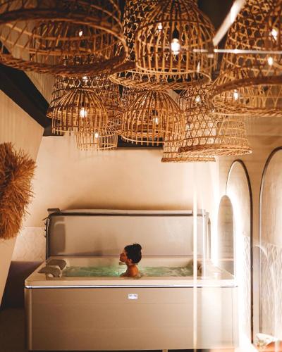 a bath tub with a teddy bear in it under a chandelier at Comme chez Soye - Private Wellness in Soye