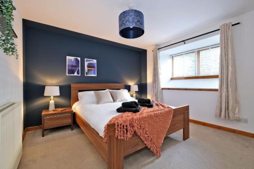a bedroom with a bed with a blue accent wall at Sensational West End Living with Bicocca Stays in Aberdeen
