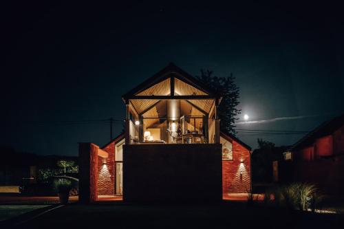 a glass house at night with the moon in the background at Comme chez Soye - Private Wellness in Soye