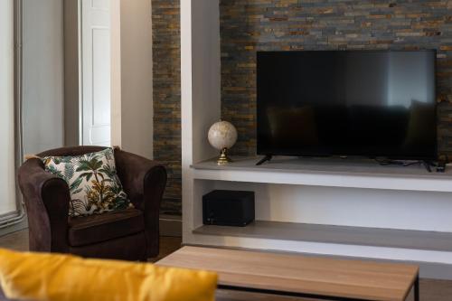 a living room with a television and two chairs at Le Fonctionnel - TravelHome in Villefranche-sur-Saône