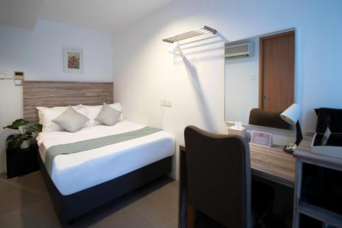 a bedroom with a bed and a desk with a lamp at Victoria Hotel a NuVe Group Collection in Singapore