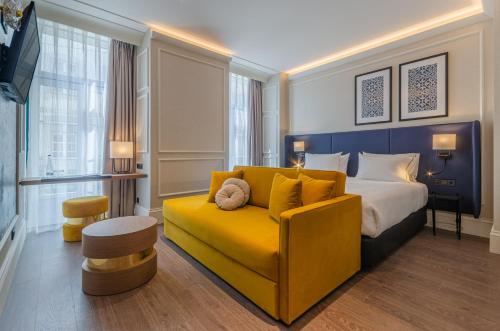 a hotel room with a bed and a yellow couch at Eurostars Lisboa Baixa in Lisbon