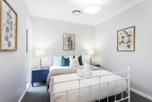 Un dormitorio con una cama blanca con toques azules en A Refreshing Mudgee Getaway at Felicitys on Court, en Mudgee