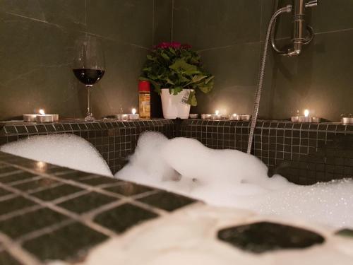 una vasca da bagno piena di neve accanto a un bicchiere di vino di Torrebeatrice a Bagnaia