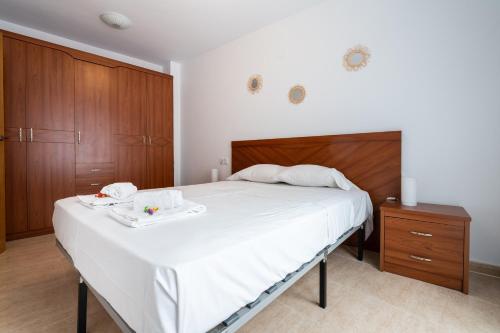 1 dormitorio con 1 cama blanca grande y armarios de madera en Excelente apartamento en 2ª línea de playa. WIFI!, en Puerto Sagunto