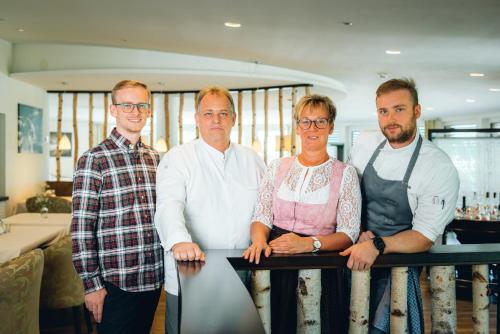 drie mannen en een vrouw die naast een tafel staan bij Hotel Birkenhöhe in Hirschegg