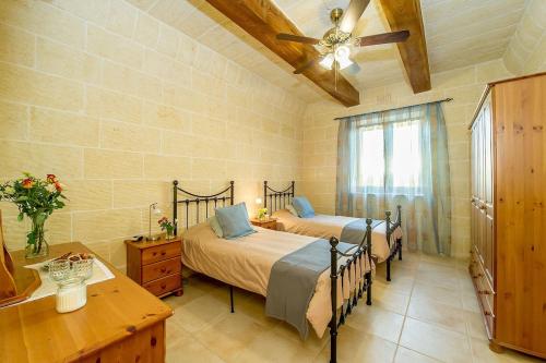 Rebbiegha Holiday Home في Qala: غرفة نوم بسريرين ومروحة سقف