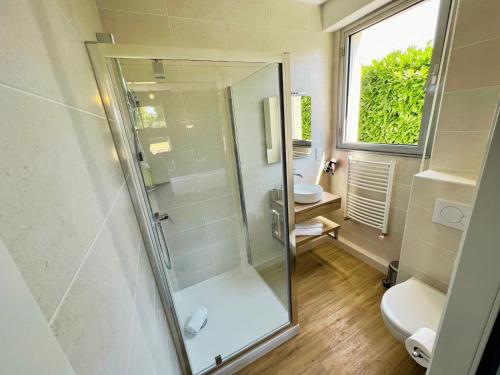 a bathroom with a shower and a toilet and a window at Hôtel de la Marine in Saint-Herblain