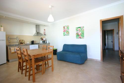 a kitchen and living room with a table and a blue chair at Villa vista mar e piscina in Fuzeta