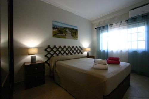 - une chambre avec un grand lit et une fenêtre dans l'établissement Villa vista mar e piscina, à Fuzeta