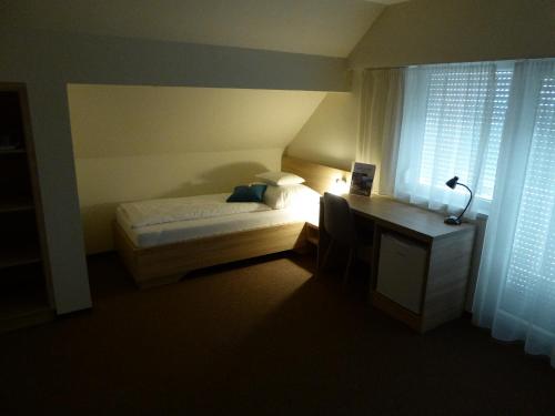 a bedroom with a bed and a desk and a window at Belvárosi Nemes Apartmanház Szekszárd in Szekszárd