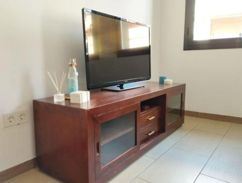 a flat screen tv sitting on top of a wooden entertainment center at Cozy flat with terrace in Palamós
