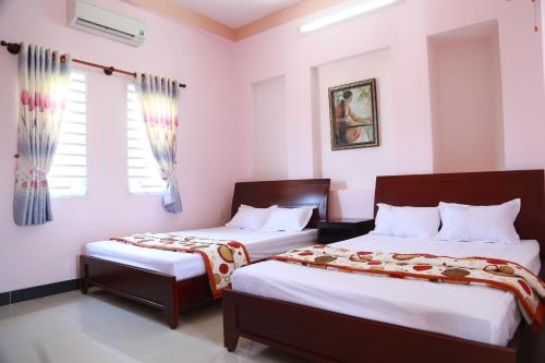 twee bedden in een kamer met witte muren en ramen bij Ban Mai Hotel 66 in Phan Thiet