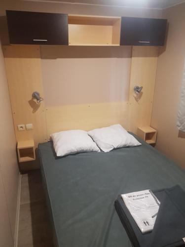 Habitación pequeña con 1 cama con 2 almohadas blancas en Coeur de Vendée mobil home, en La Boissière-de-Montaigu