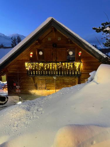 a cabin covered in snow with christmas lights on it at Chalet La joue du Loup in Le Dévoluy