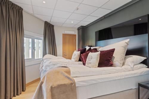 a bedroom with a large white bed with pillows at Quality Hotel Saga in Tromsø