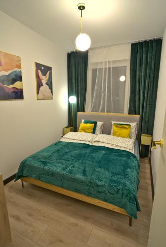 a bedroom with a bed with a green blanket at Apartament Witold in Biała Podlaska