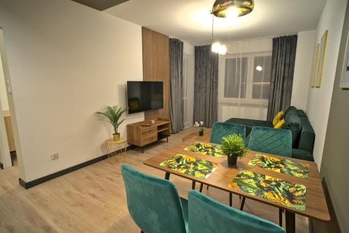 sala de estar con mesa, sillas y TV en Apartament Witold en Biała Podlaska