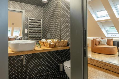 a bathroom with a sink and a toilet and a chair at Vila Na Landeku in Ostrava
