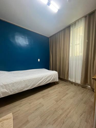 a bedroom with a bed and a blue wall at sodam stay in Jeju