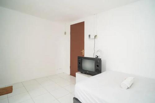 1 dormitorio con 1 cama y TV. en KoolKost near Margo City Mall en Depok