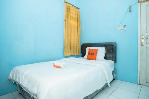 Habitación azul con cama con almohada naranja en KoolKost near Margo City Mall en Depok