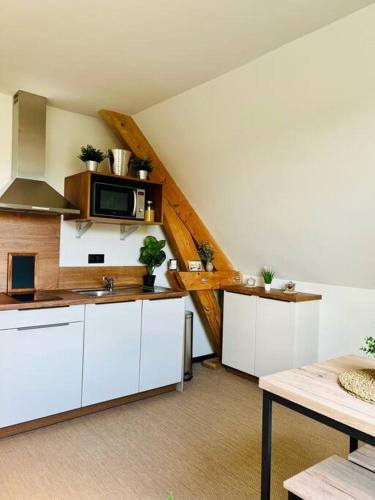 une cuisine avec des armoires blanches et un micro-ondes dans l'établissement Chez Pierrette à deux pas du Château de Meursault, à Meursault