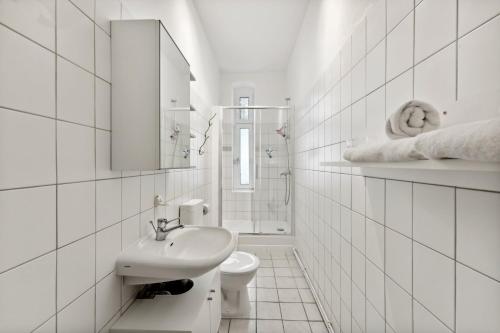 La salle de bains blanche est pourvue d'un lavabo et de toilettes. dans l'établissement Sweet Central Tiny Apartment for 4 People, à Berlin