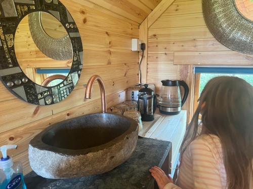 a woman standing in front of a sink in a tiny house at The Hobbit Hole in Zelah