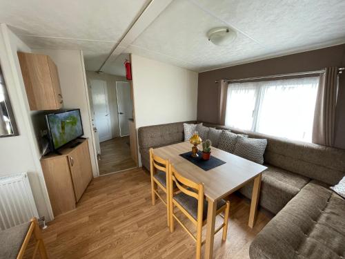 a living room with a table and a couch at Impeccable 4-Bed Caravan in Clacton-on-Sea in Clacton-on-Sea