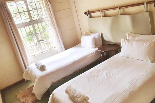 two beds in a room with a window at Remarkable 3-Bed Cottage in Nyanga in Juliasdale